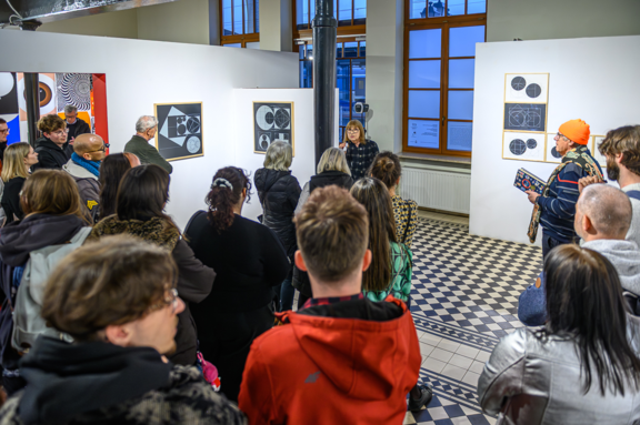 Oprowadzanie po wystawie przez artystkę Teresę Bujnowską. W tle jej prace, należące do kolekcji Małopolskiej Fundacji Muzeum Sztuki Współczesnej